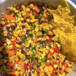 Black bean and corn salad in a large white mixing bowl with tortilla chips