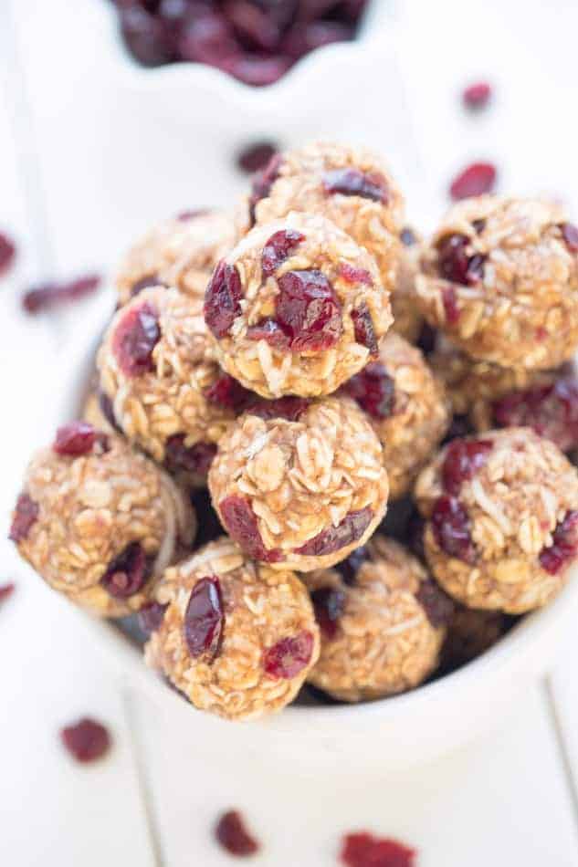 White bowl of Cranberry Energy Bites with oats and cranberries on a white wooden table.