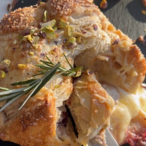 Puffed pastry wrapped around baked brie on a baking sheet