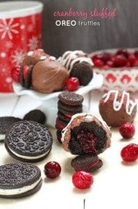 Half of a cranberry stuffed oreo truffle showing the inside with oreos and cranberries scattered nearby