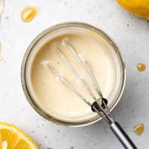 Top view of blended lemon tahini dressing in a glass jar with a whisk