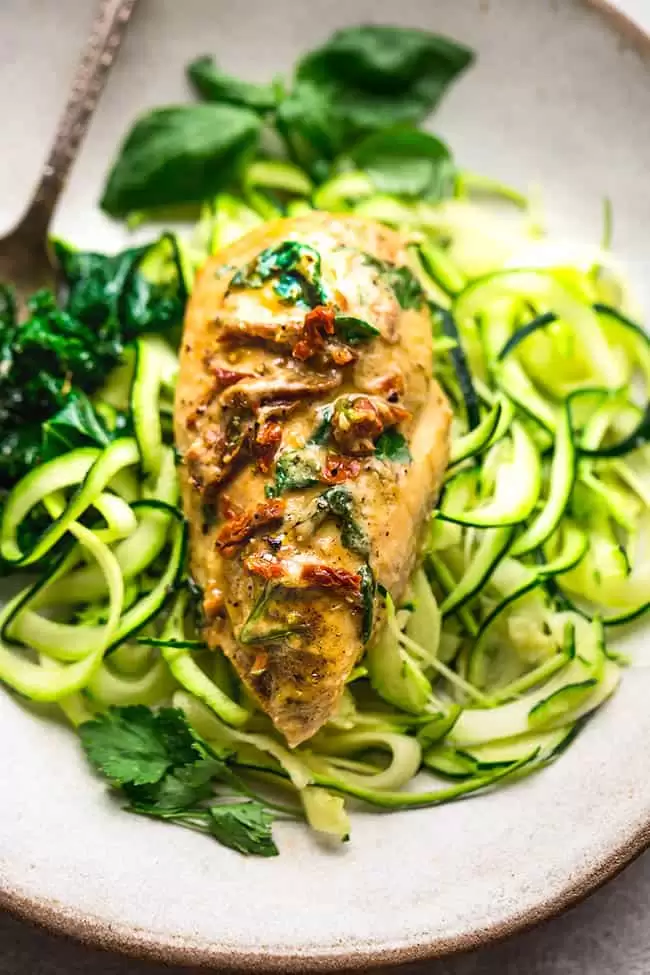 Close up of Creamy Sun-Dried Tomato Chicken Breast over zucchini noodles on plate