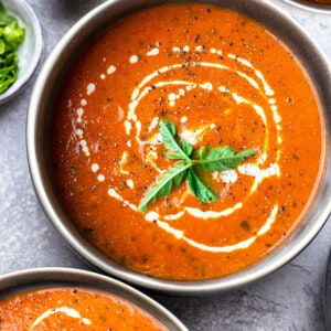 Top view of one bowl of Whole30 tomato soup on a grey background