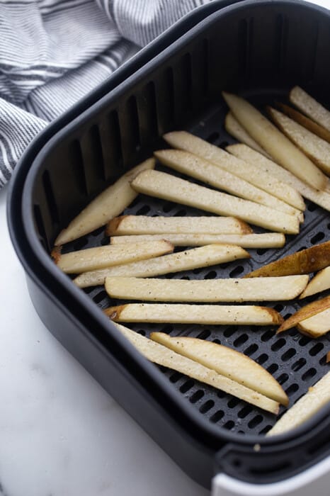A batch of uncooked french fries in an air fryer basket