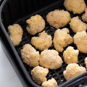 Coated uncooked cauliflower wings in an air fryer basket