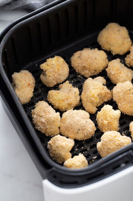 Coated uncooked cauliflower wings in an air fryer basket