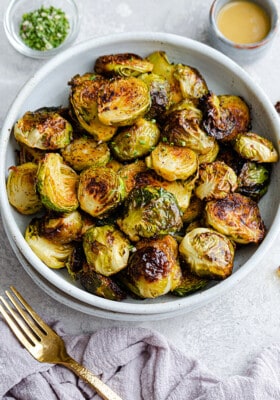 Top view of air fryer Brussels sprouts in a white bowl with a gold fork on the side