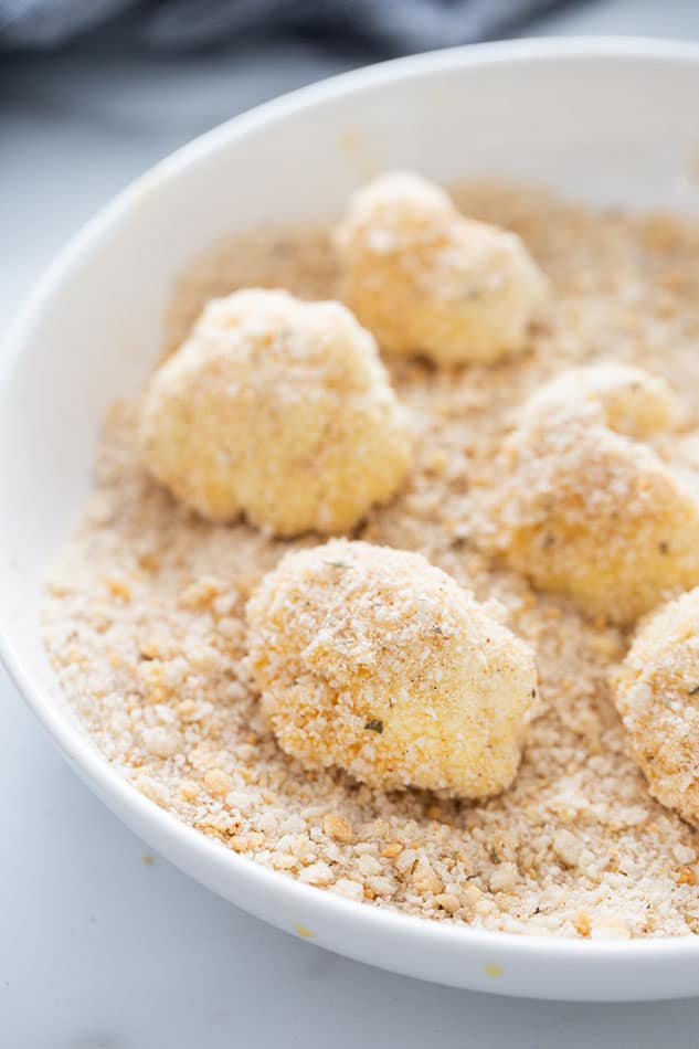 Raw cauliflower florets covered in an almond meal breading mixture