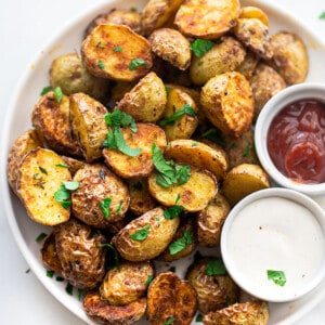 A close-up shot of crispy roasted potatoes on a plate with chopped fresh parsley on top