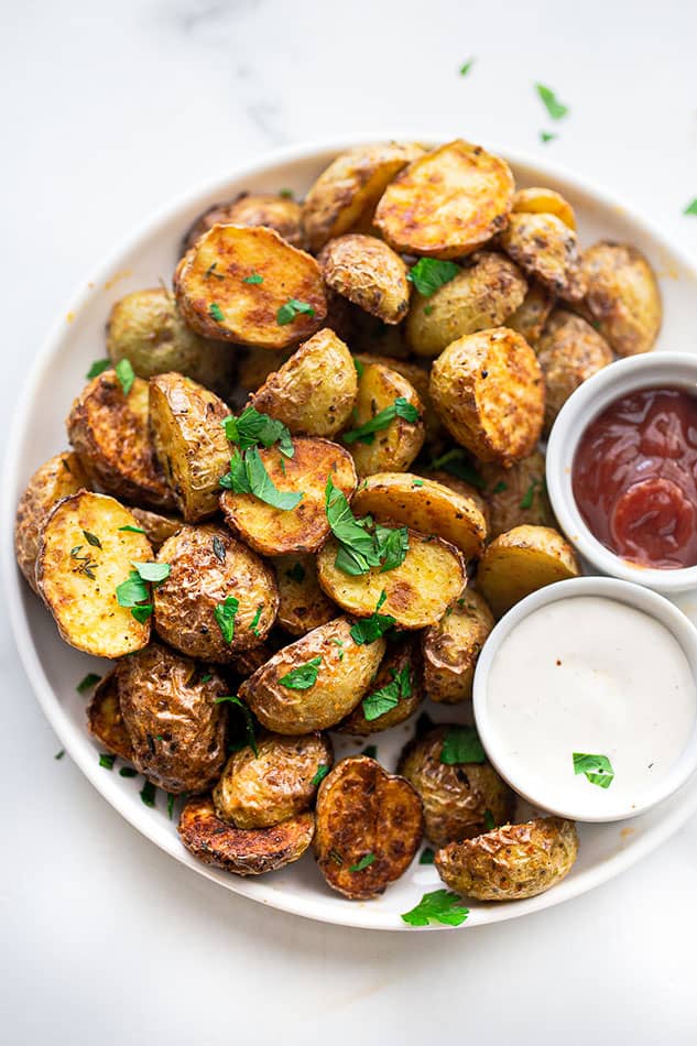 A close-up shot of crispy roasted potatoes on a plate with chopped fresh parsley on top