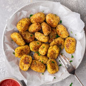 Overehead view of a batch of cauliflower tots in a white bowl with a fork