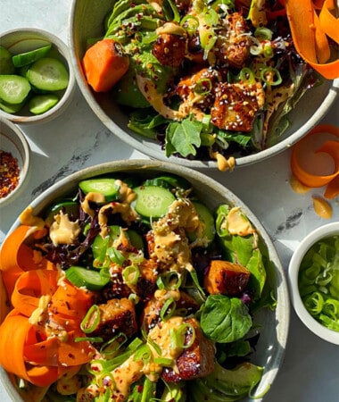 2 Bowls of salmon bites served over mixed greens, carrots, cucumber and avocado.