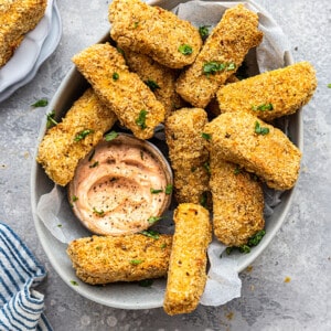 A pile of tofu fries in a an oval dish with creamy spicy dip