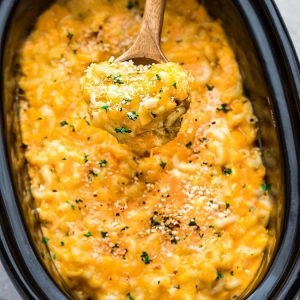 Crock Pot Macaroni and Cheese being served with a wooden spoon