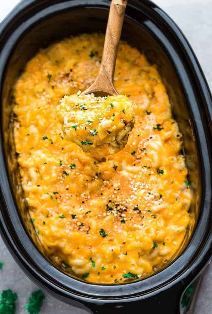 A Wooden Spoon Scooping Out a Large Bite of Mac and Cheese From a Crock Pot