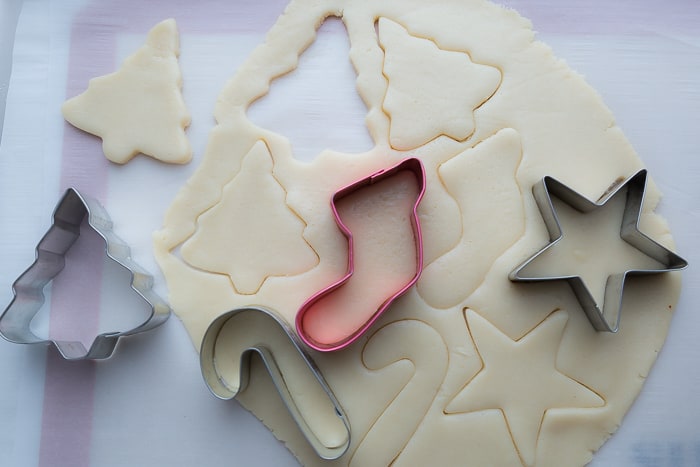 Top view of raw sugar cookie dough cut into shapes on parchment paper