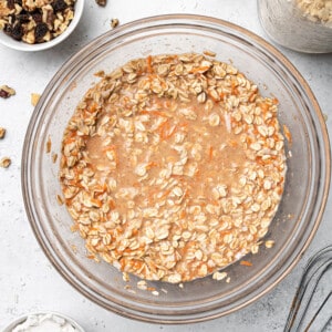 Mixed rolled oats and wet ingredients in a clear bowl