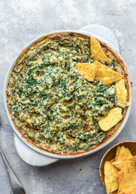 Top shot of Vegan Spinach Dip in a white round baking dish with gluten free tortilla chips