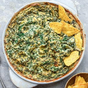 Top shot of Vegan Spinach Dip in a white round baking dish with gluten free tortilla chips
