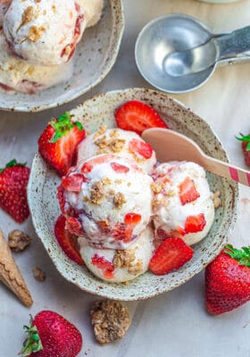 Top view of paleo strawberry cheesecake ice cream in a bowl with a wooden spoon