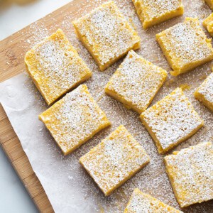 Overhead view of Lemon Bars dusted with powdered sugar on a wooden cutting board