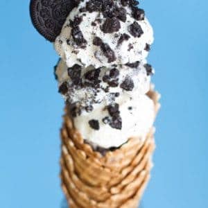 No churn vanilla ice cream in a stack of cones topped with oreo crumbs