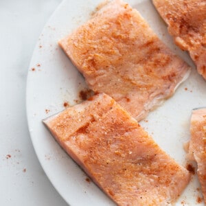 Three Salmon Fillets Placed Evenly Apart on a white plate