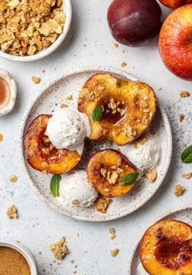 Three air fryer apple halves topped with ice cream on a white plate