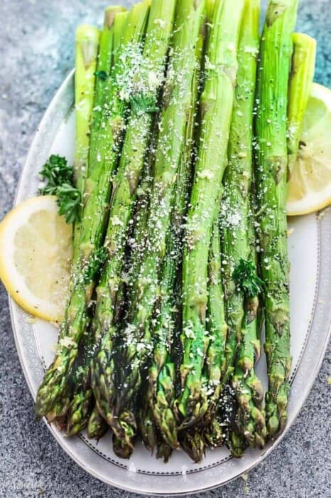 Asparagus spears on a platter seasoned with salt and lemon