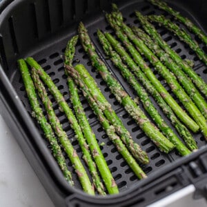 Fresh asparagus stalks in an air fryer basket