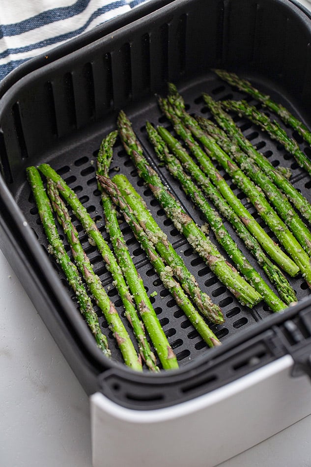 Fresh asparagus stalks in an air fryer basket