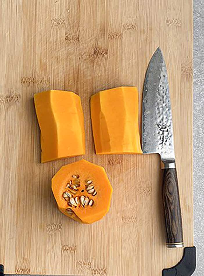 A peeled and halved butternut squash on a wooden cutting board