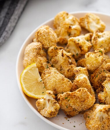 Crispy cauliflower wings with a lemon wedge in a white bowl