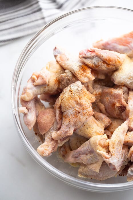 Raw marinated chicken wings in a clear bowl