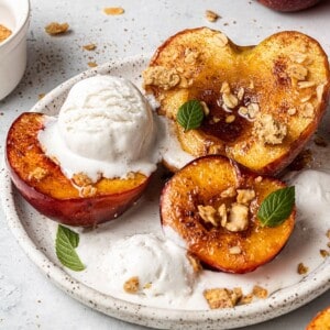 Close-up of three air fryer peach halves topped with ice cream on a white plate