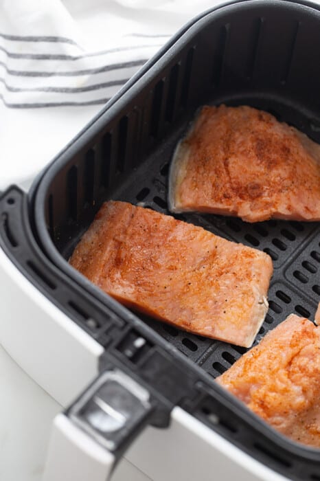 Three Salmon Fillets Placed Evenly Apart in an Air Fryer Basket