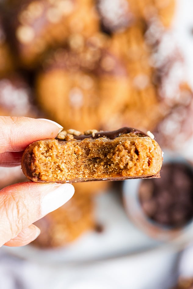 A hand holding a chocolate-dipped Almond Flour cookie with a bite out of it