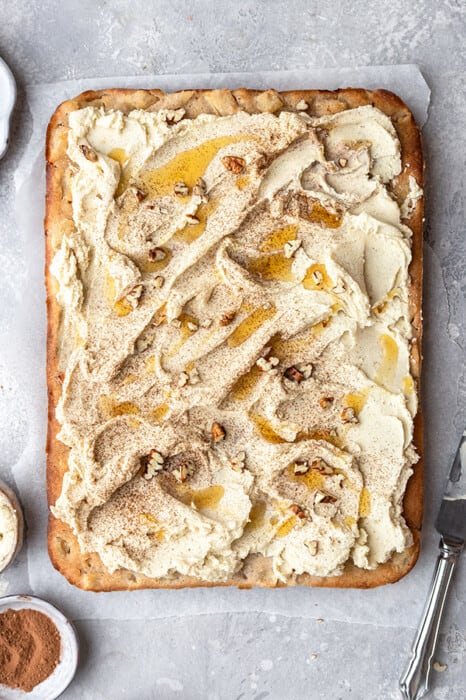 Overhead view of a frosted apple cake with chopped nuts