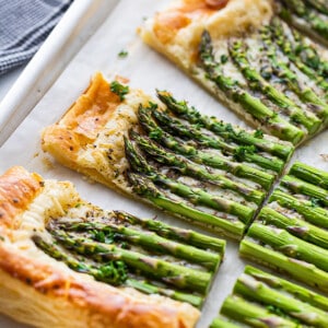 Four sliced squares of a baked asparagus tart on a baking sheet