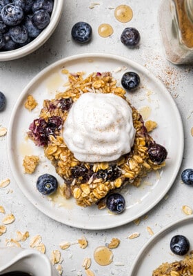 A slice of baked oatmeal on a small plate with a scoop of Greek yogurt on top