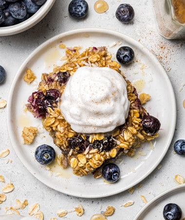 A slice of baked oatmeal on a small plate with a scoop of Greek yogurt on top