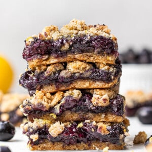 Side view of four blueberry crumb bars stacked on a white background