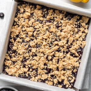 Unbaked blueberry crumble mixture with blueberry filling in square baking pan