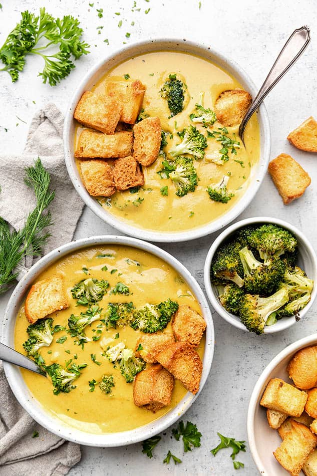 Two Vegan Broccoli Soups in white bowls with toasted sour dough slice