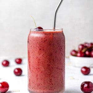 Side angle of one easy cherry smoothie in a glass with a straw