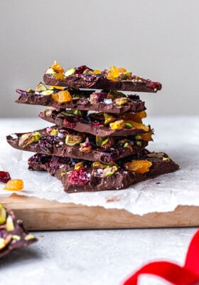 Side view of a stack of dark chocolate bark pieces with pistachios and dried fruit