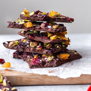 Side view of a stack of dark chocolate bark pieces with pistachios and dried fruit