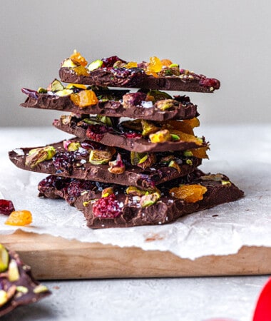 Side view of a stack of dark chocolate bark pieces with pistachios and dried fruit