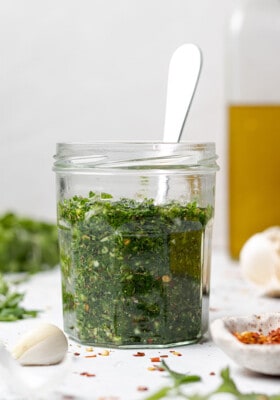 Side view of easy chimichurri sauce in a small jar with a spoon