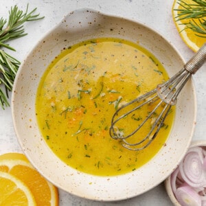 Orange vinaigrette in a white bowl with a whisk
